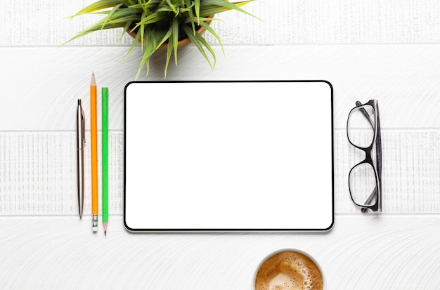 tablet with blank screen on desk coffee cup and office supplies top view flat lay with copy space