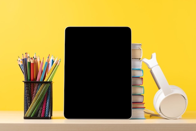 Tablet with colorful pencils and stack of books