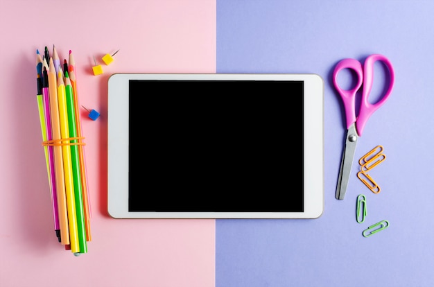 A tablet with an empty screen and office supplies