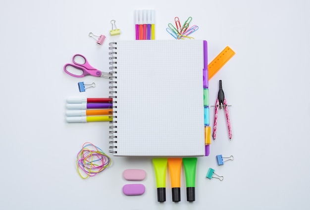 A tablet with an empty screen and school supplies on a black background