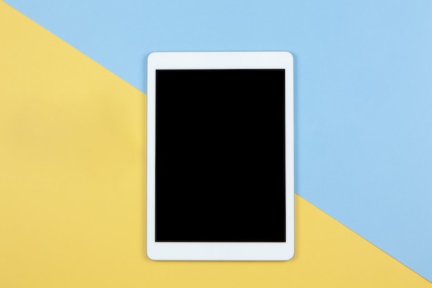 Tablet with empty screen on yellow and blue background