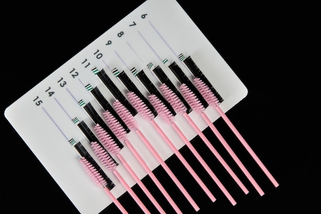 A tablet with false eyelashes and brushes on a black background