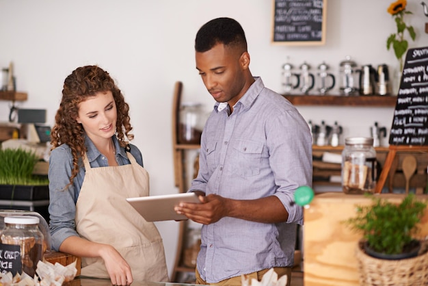 Tabletcafé barista en teamwerk van mensen discussie en training in coffeeshop Obers zwarte man en vrouw in restaurant met technologie voor voorraadcontrole of verkoopbeheer in de winkel