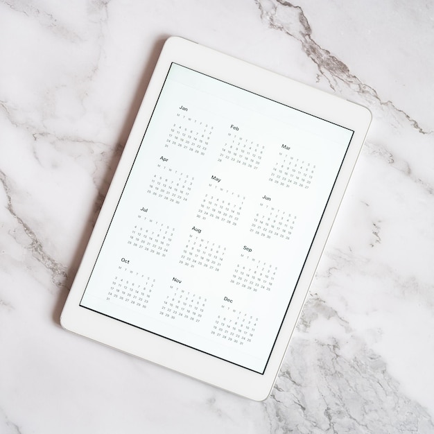 Tabletcomputer met een open app van kalender voor niet-gespecificeerde datum jaar zonder datum op een grijze marmeren achtergrond concept zaken of takenlijst doelen met technologie met behulp van bovenaanzicht plat lag vierkant