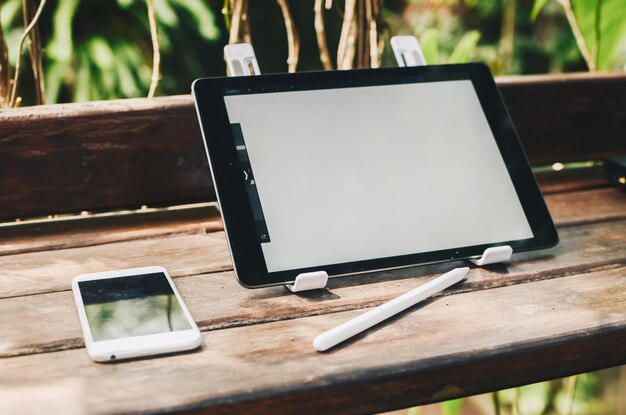 Tabletcomputer met wit scherm op houten tafel buiten