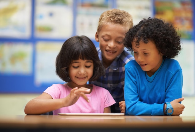 Tabletondersteund leren Drie scholieren werken aan een digitale tablet in de klas