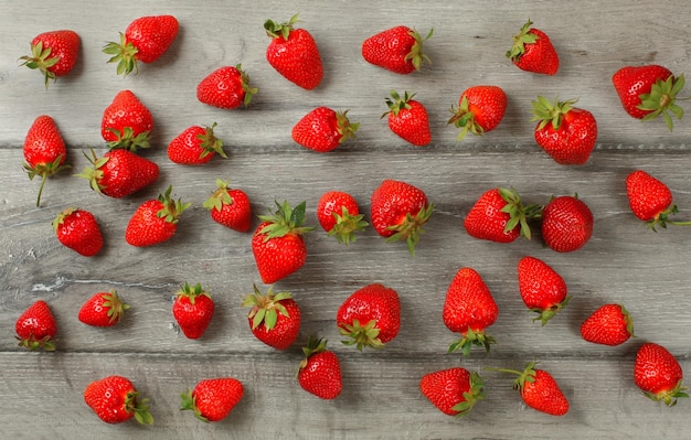 Tabletop view - ripe strawberries, freshly picked spilled on gray wood boards desk