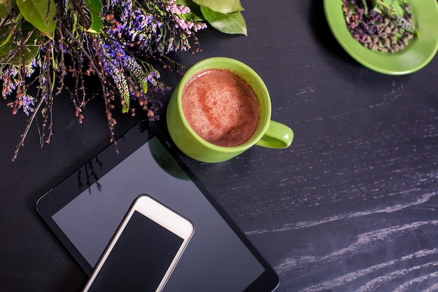 A tabletop with a cup of coffee and a bouquet of flowers on it.