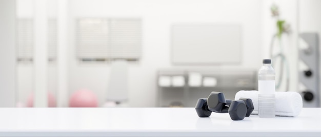 Tabletop with dumbbells water bottle towel and copy space over blurred bathroom background