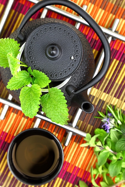 Tabletop with oriental teapot and cup with fresh herbs