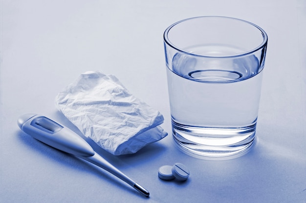 Tablets, clinical thermometer and glass of water