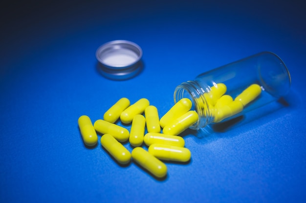 Tablets and pills on a blue background, a bottle for tablets.