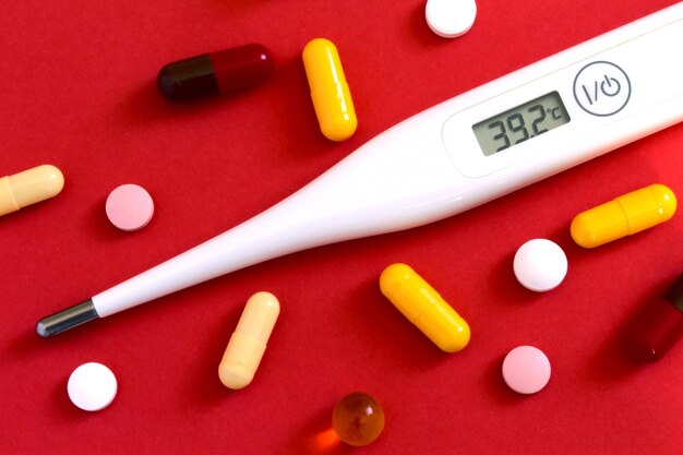 tablets and a thermometer on a red background