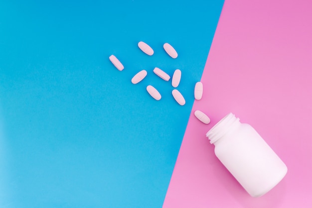 Tabletten en een fles op een fel gekleurde achtergrond. Medische plat lag lay-out op de roze en blauwe achtergrond