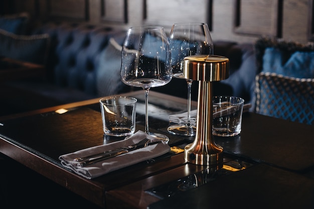 Photo tableware glasses, flower fork, knife served for dinner in restaurant with cozy interior