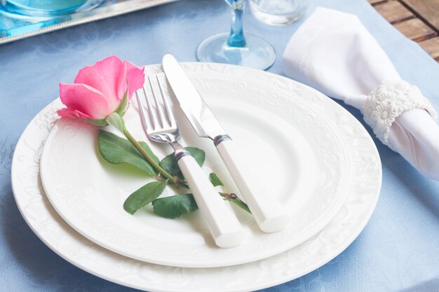 Tableware set of plates, cups and utencils with rose