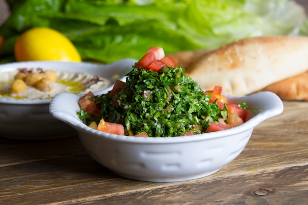 Tabouleh served in a dish side view on wooden table background