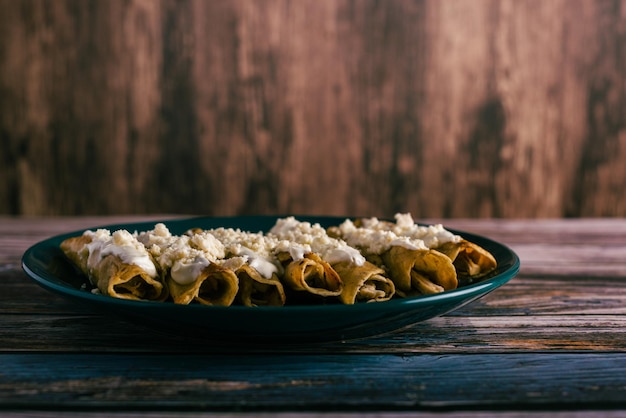 Taco's flauta met kaas en room op een houten tafel Mexicaanse snacks