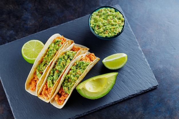 Taco's met kip en guacamole op een donkere achtergrond. Mexicaanse taco's met gebakken gehakt op een leisteen bord. Traditioneel gerecht uit de Mexicaanse keuken