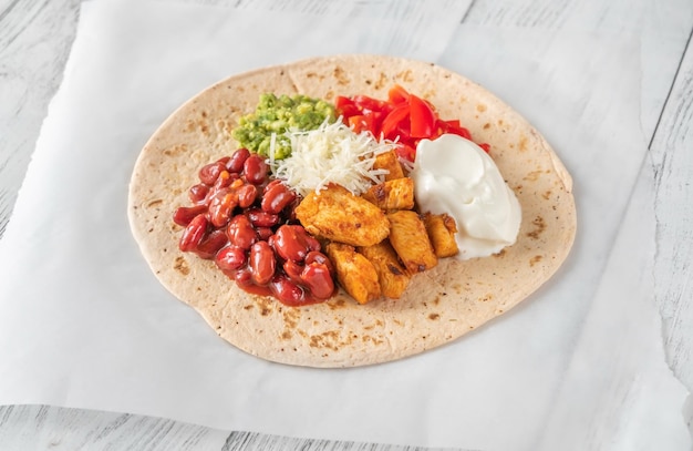 Taco with chicken and vegetable filling on the wooden background