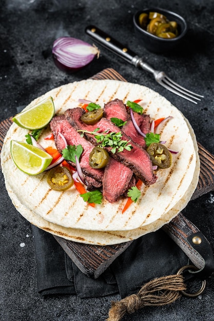 Tacos of mexican beef fajitas alambre with onion jalapeno and bell pepper Black background top view