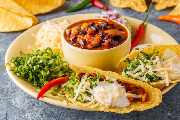 Tacos with chili con carne, salad, cheese and sour cream