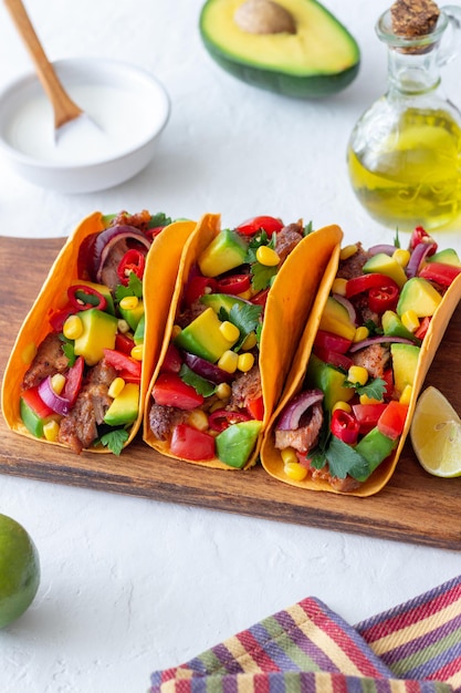 Tacos with pork, avocado, tomatoes, corn and onions. Mexican food.