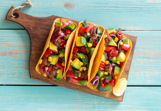 Tacos with pork, avocado, tomatoes, corn and onions. Mexican food.