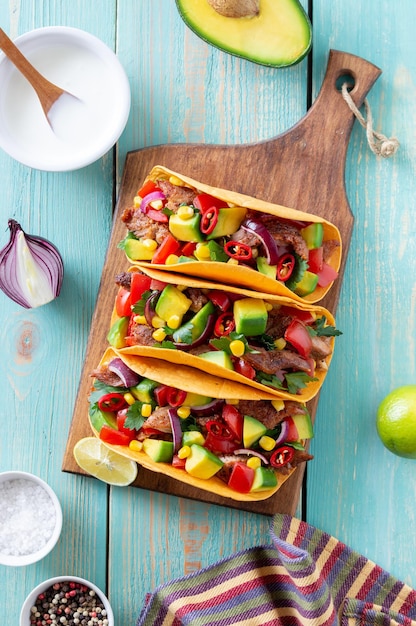 Tacos con carne di maiale, avocado, pomodori, mais e cipolle. cibo messicano.