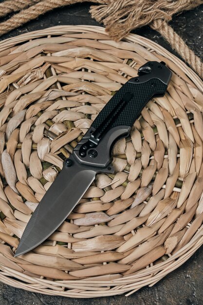 Tactical folding knife lies on pano woven from reeds