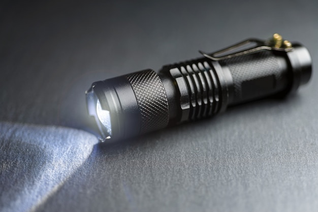Tactical waterproof flashlight. LED flashlight shines on the table in smoke..