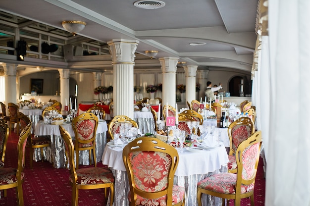 Tafel bij het bruiloftsbanket in het restaurant, klassieke stijl met witte tafelkleden en servetten, vazen met bloemen.