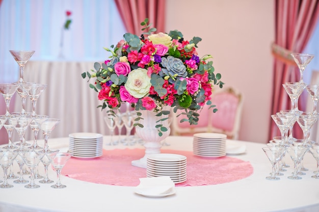 Tafel bij het bruiloftsbanket in het restaurant, klassieke stijl met witte tafelkleden en servetten, vazen met bloemen.