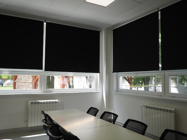 Tafel en stoelen in de vergaderruimte op kantoor in de klas of in de bibliotheekzaal Witte zwarte en grijze verf in het interieur Zwarte jaloezieën om de kamer te verduisteren Modern interieurontwerp