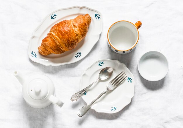 Tafel geserveerd voor ontbijt theekransjes vintage witte gerechten croissant theepot op een lichte achtergrond bovenaanzicht