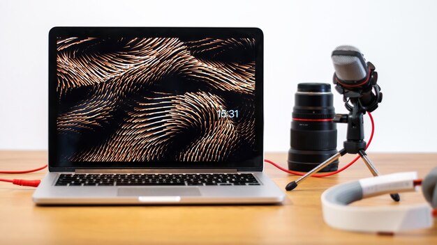 Tafel met dingen die content maken. Laptop, microfoon, cameralens en koptelefoon. Werken vanuit huis