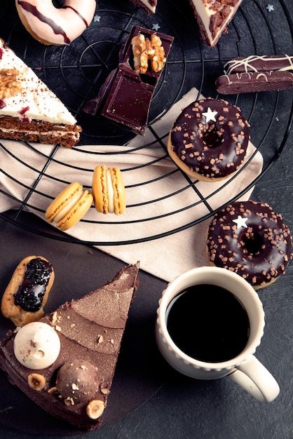 Tafel met verschillende koekjes, donuts, taarten, cheesecakes op donkere achtergrond. Heerlijke desserttafel. Bovenaanzicht plat gelegd