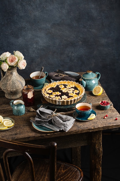 Tafel met warme bessentaart, warme kopjes met citroenthee, jam en bloemen