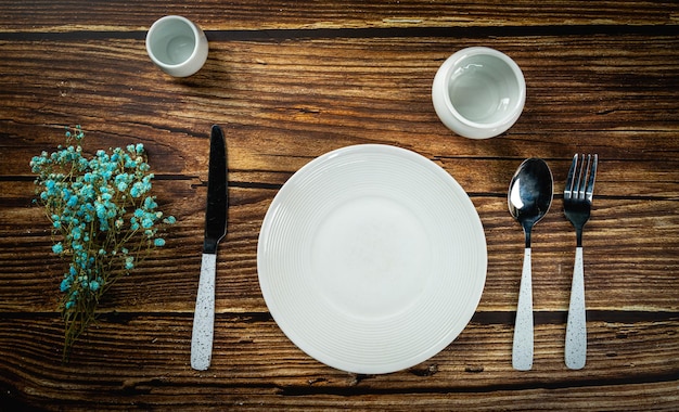 Tafel opgezet met witte plaat en lepel op houten achtergrond bovenaanzicht