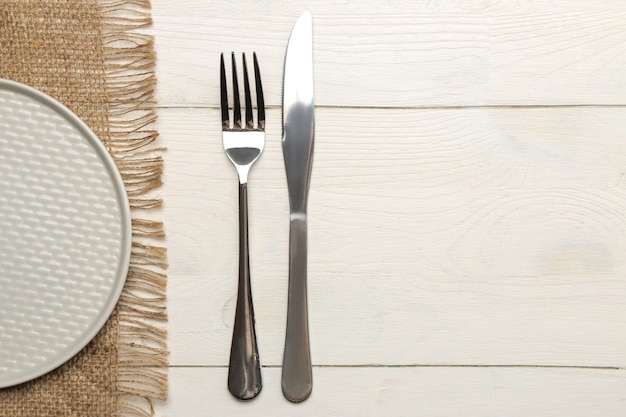 Tafel opstelling. bestek. Vork, mes en grijze plaat op een witte houten tafel. bovenaanzicht