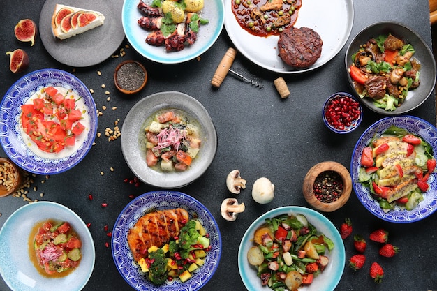 Tafel vol met eten bovenaanzicht. Set gerechten op tafel. vleessalade en dessert op tafelblad bekijken.