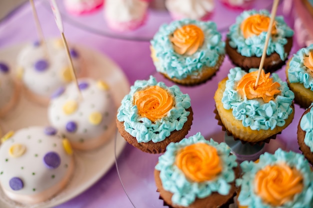 tafel voor kinderen met cupcakes met blauwe en oranje top en decoritems in fel roze en blauw