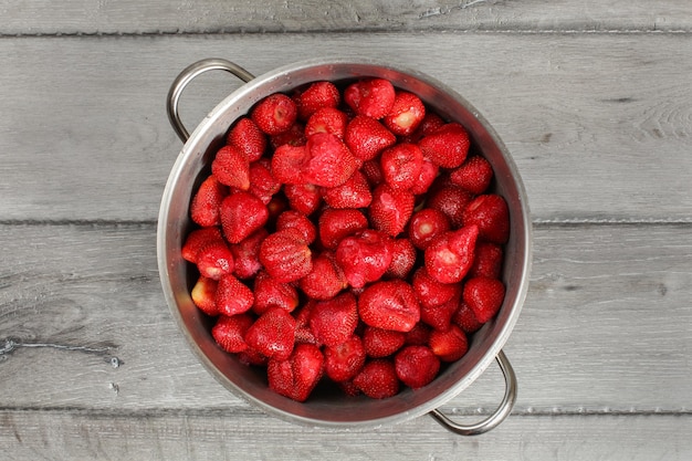 Tafelblad uitzicht, stalen pot vol aardbeien met bladeren verwijderd. zelfgemaakte aardbeienjam bereiding.