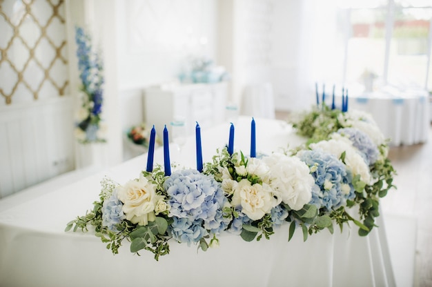 Tafeldecoratie bruiloft met blauwe bloemen op de tafel in het tafeldecor van het restaurant voor het diner op de bruiloft.