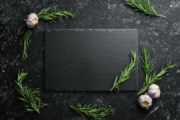 Tafelinstelling Leisteen zwarte stenen plaat met rozemarijn en knoflook Bovenaanzicht Gratis kopieerruimte