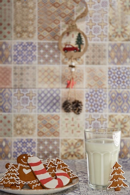 Tafelopstelling van handgemaakte koekjes en warm glas melk op de houten vintage tafel Fluffy trendy kerstversieringen Esthetische sfeer Leuke kersttraditie melk voor de kerstman