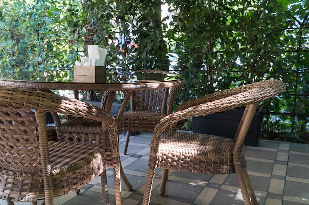 Tafels en rieten stoelen in openlucht zomercafé met bloembedden