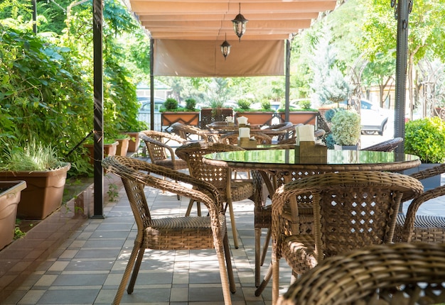 Tafels en rieten stoelen in openlucht zomercafé met bloembedden