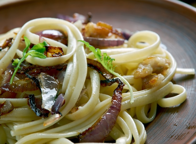 Tagliatelle alla Trevisana. Italiaanse pasta met gebakken spek en uien. Venetiaanse keuken