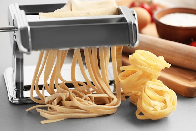 Tagliatelle maken met pastamachine op keukentafel